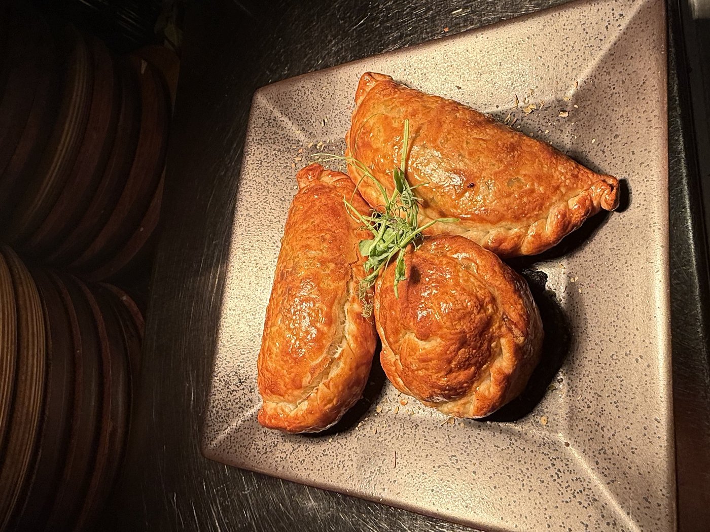 Three golden Argentine baked empanadas on a square plate at Renzo's St. Pete