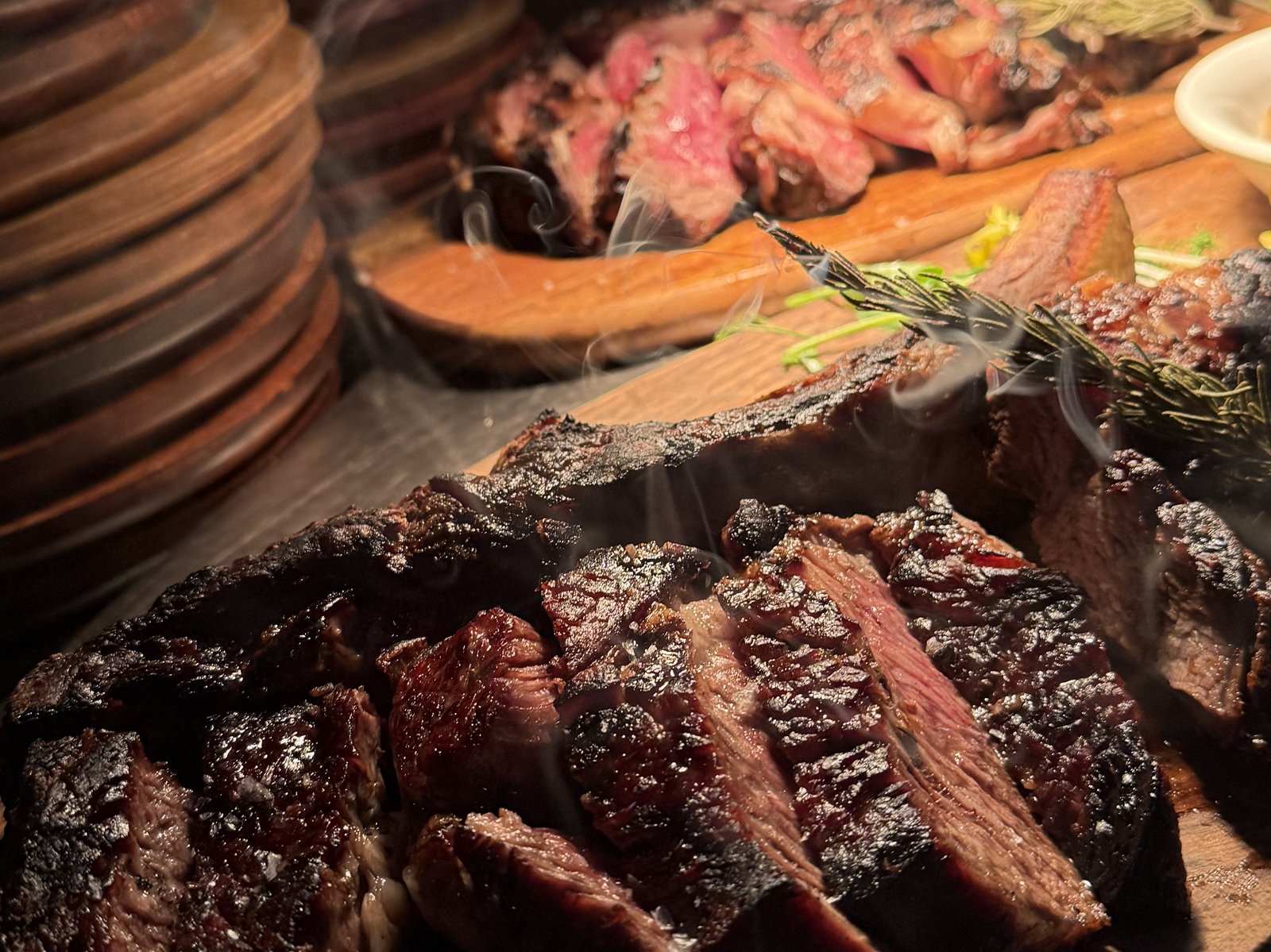 Long-bone ribeye carved on a wooden board, smoke still rising off the Josper grill at Renzo's St. Pete
