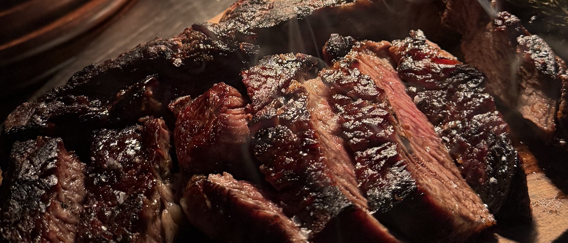 Bone-in ribeye carved on a wooden board, smoke rising — private dining at Renzo's St. Pete