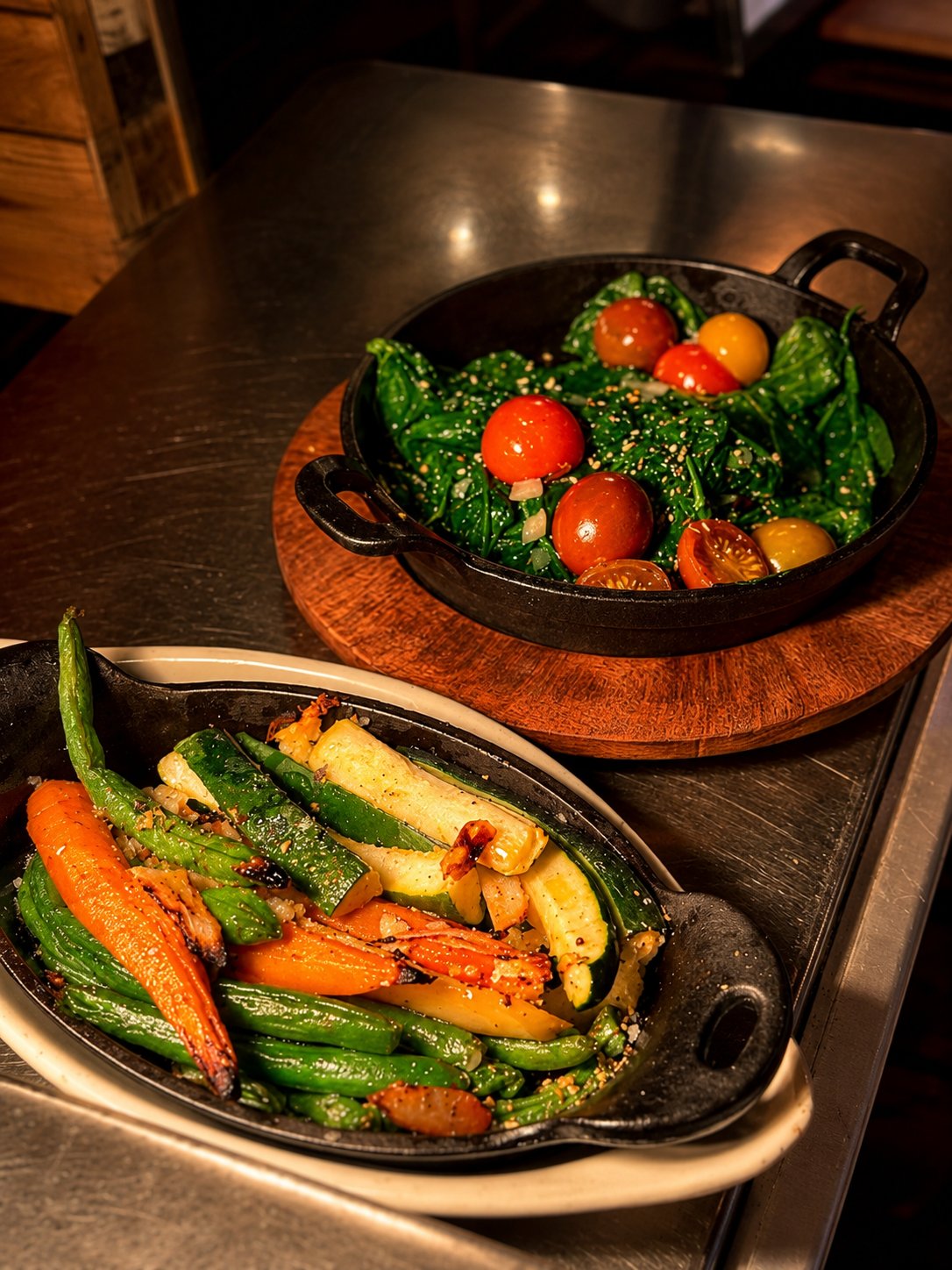 Two cast-iron sides — sautéed greens with cherry tomatoes and fire-roasted vegetables — at Renzo's St. Pete