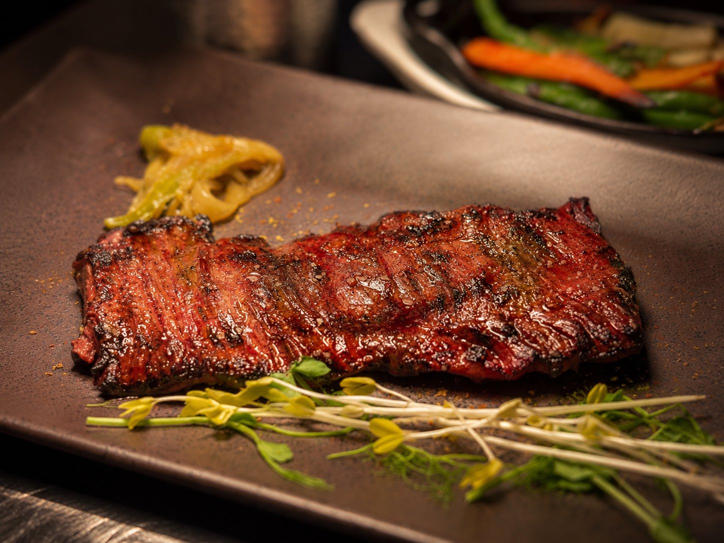 Josper-grilled skirt steak — entraña, charred and sliced al punto — on a dark plate at Renzo's St. Pete
